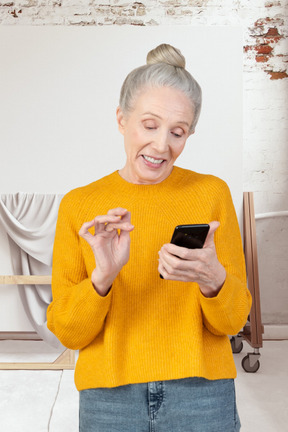 A woman in a yellow sweater looking at her cell phone