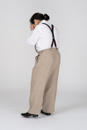 Sad man in suspenders covering face