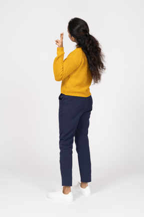 Rear view of a girl in casual clothes showing v sign