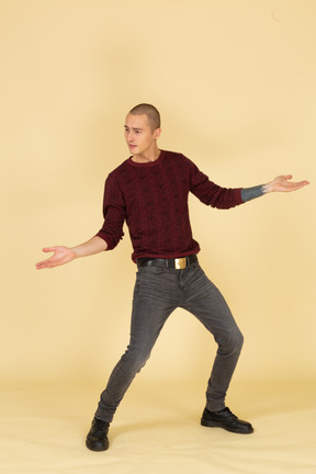 Vista frontale di un giovane uomo in pullover rosso in piedi con le gambe e le braccia diffuse