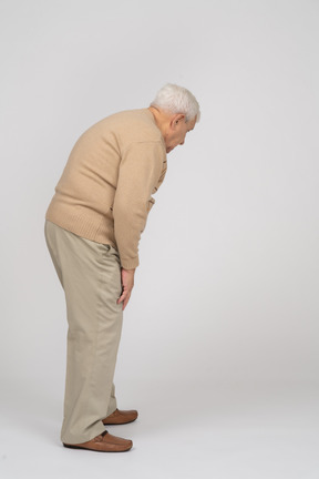 Side view of an old man in casual clothes bending down