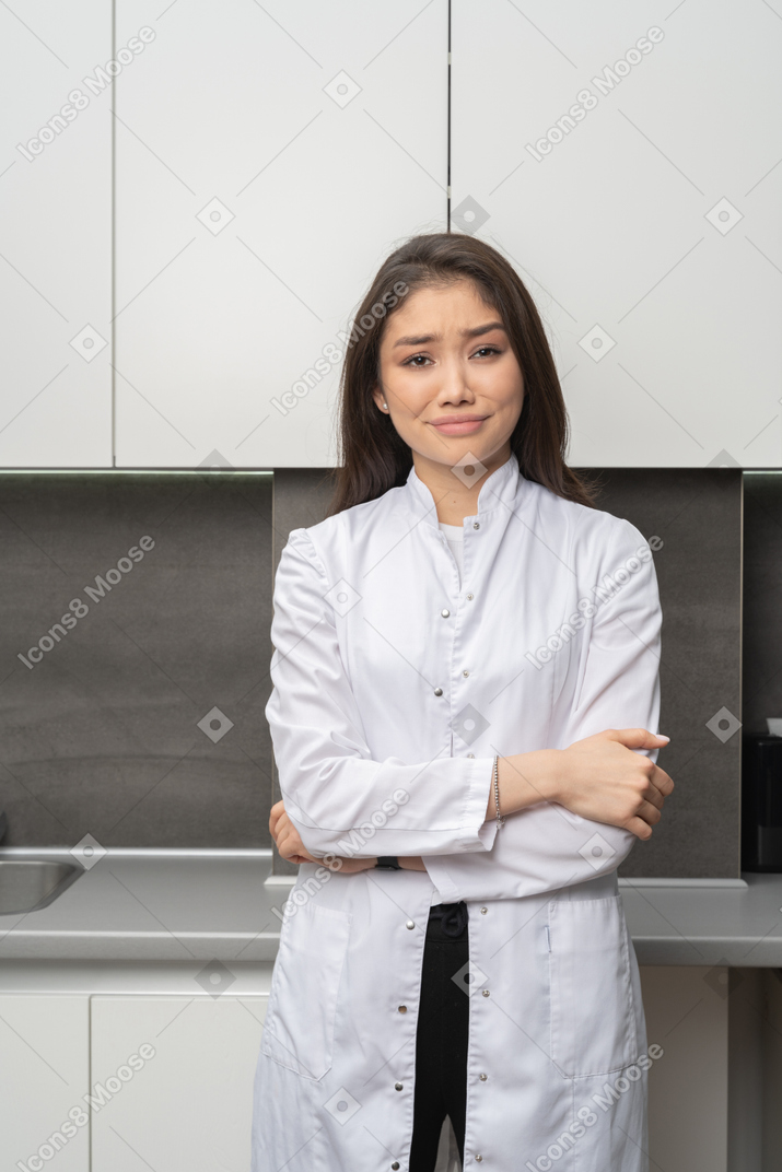 Front view of a perplexed female doctor looking at camera and crossing hands