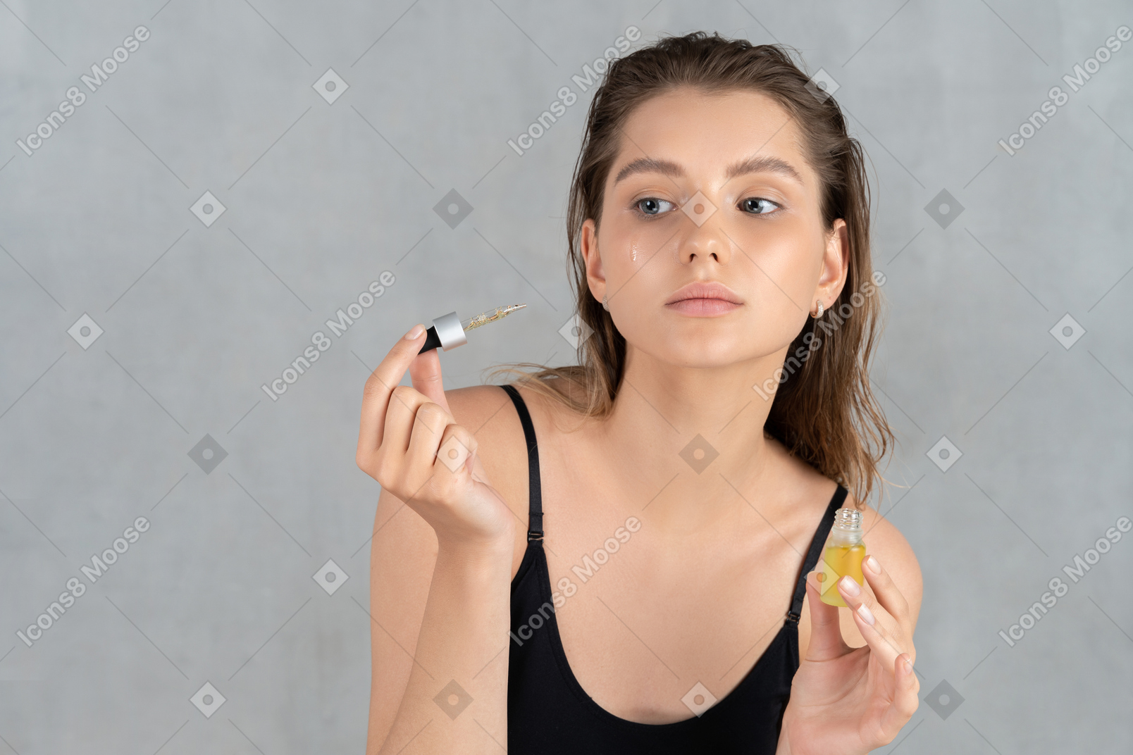 Vue de face d'une jeune femme utilisant un sérum pour le visage