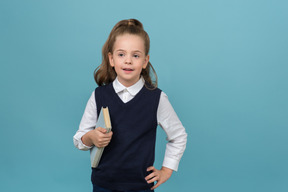 Little schoolgirl holding a book and pointing up something