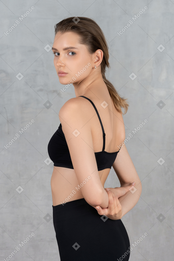 Portrait of a confident young woman standing with arms behind her back