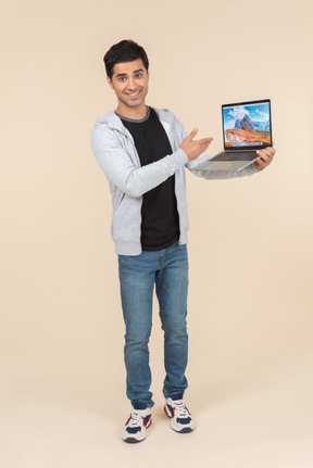 Young caucasian man presenting laptop