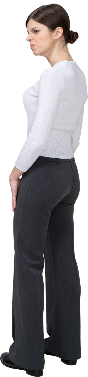 Three-quarter back view of a young woman in office clothing blowing cheeks