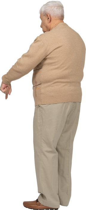 Side view of an old man in casual clothes pointing down with finger