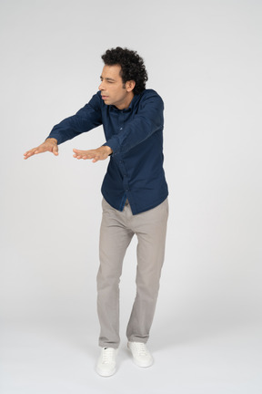 伸ばした腕で立っているカジュアルな服装の男性の正面図