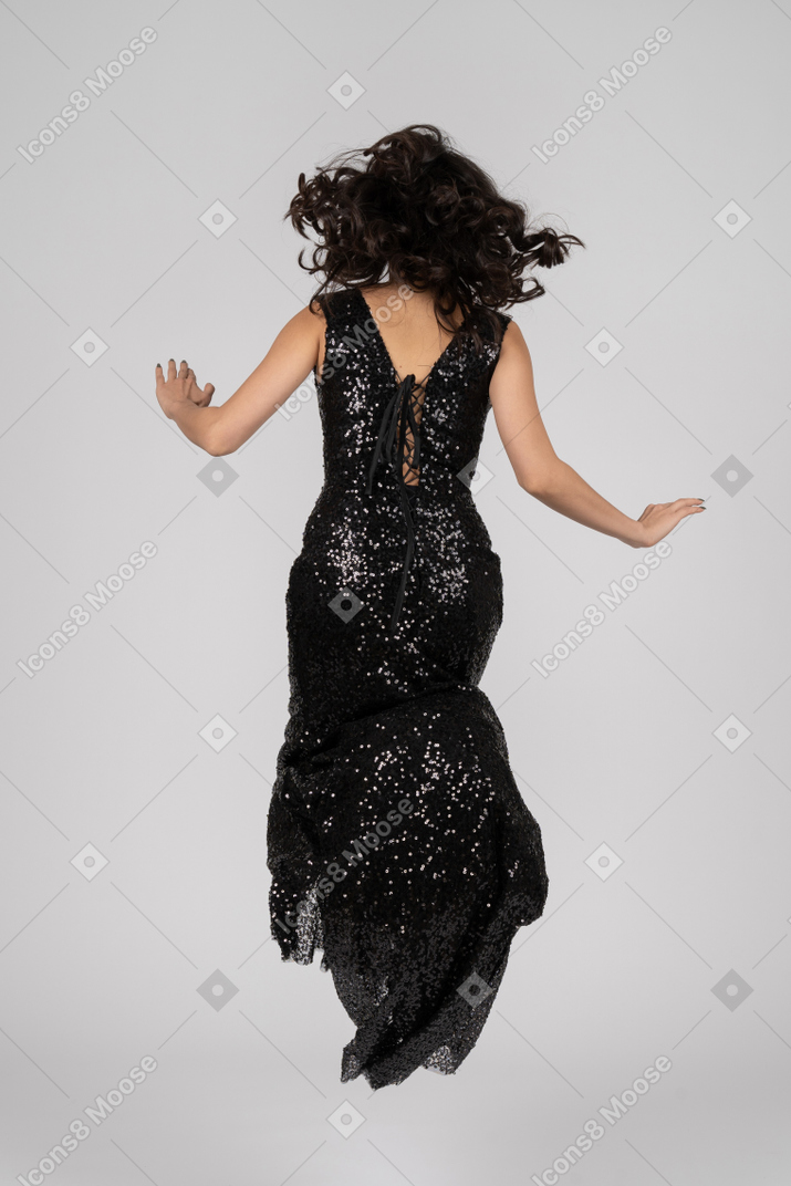 Beautiful woman in black evening dress jumps