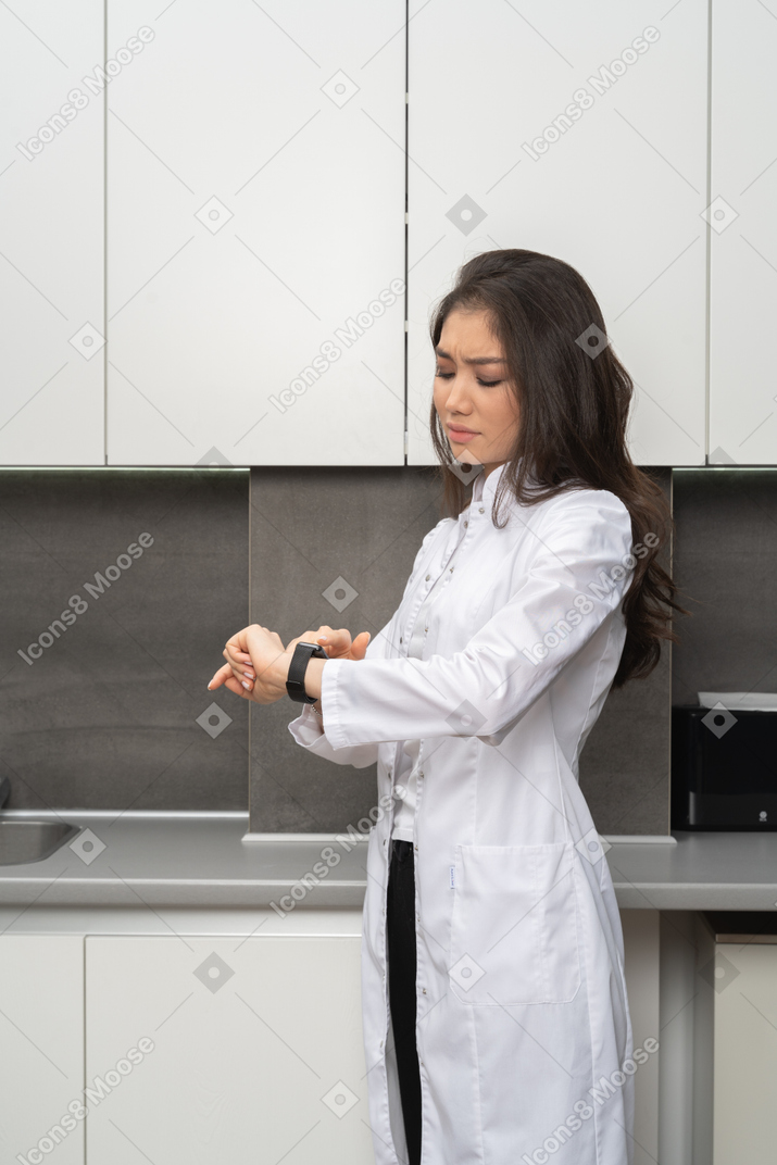 Primo piano una dottoressa scontenta guardando il suo orologio
