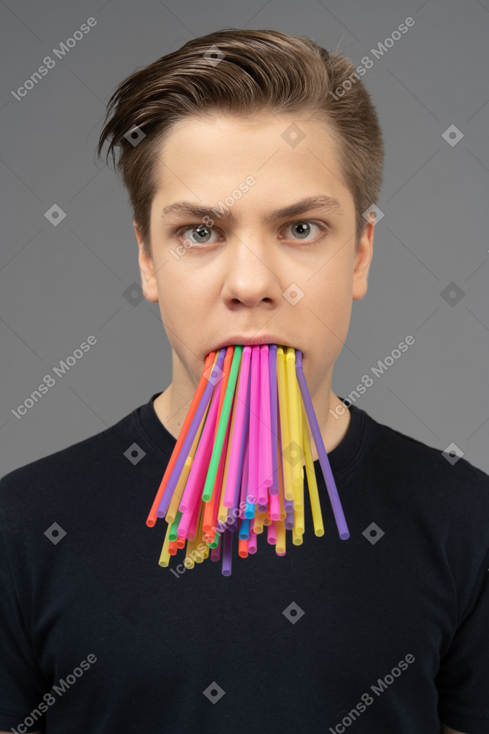 Homem segurando canudos de plástico na boca, olhando para a câmera