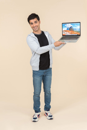 Young caucasian man presenting laptop