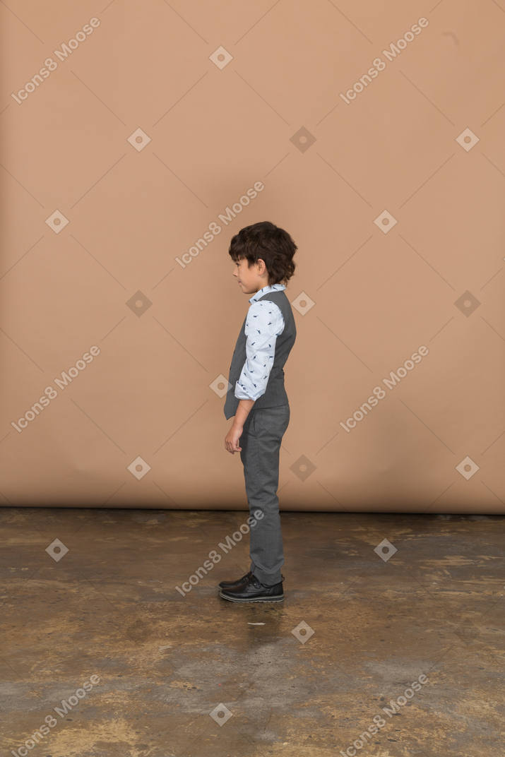 Boy in grey suit standing in profile