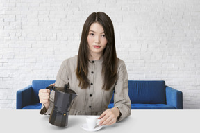 Mujer joven sirviendo café en una taza