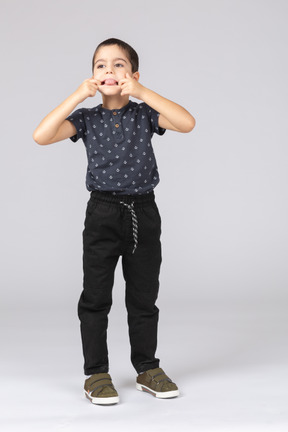 Vista frontal de un chico lindo poniendo los dedos en la boca y mostrando la lengua