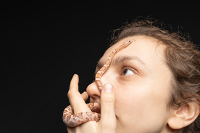 Pequeña serpiente arrastrándose sobre la frente de una mujer joven