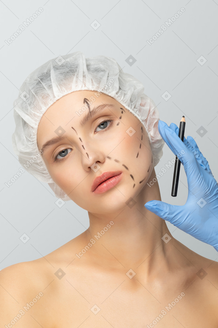 A woman in a surgical cap getting her face marked