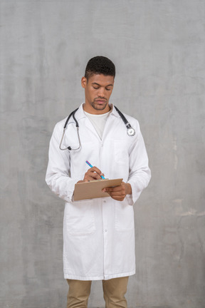 Front view of young male doctor making notes