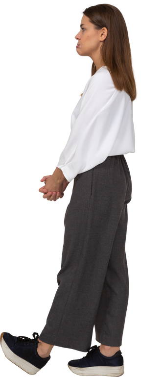 Vista lateral de uma jovem descontente com roupas de escritório, de mãos dadas
