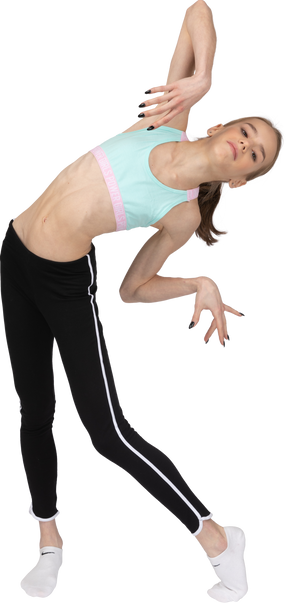 Front view of a teen girl in sportswear tilting and raising hands