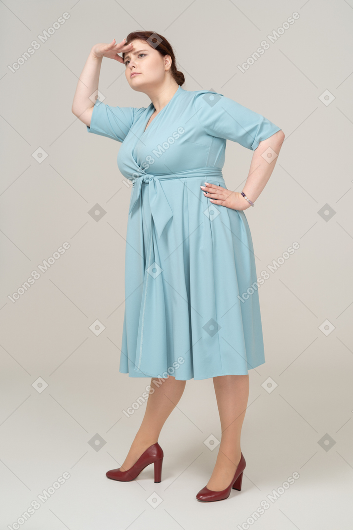 Vue de face d'une femme en robe bleue à la recherche de quelqu'un
