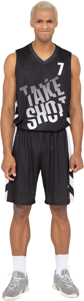 Вид спереди недовольного молодого баскетболиста, сжимающего кулаки