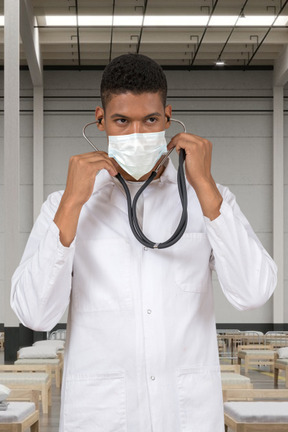 A man in a lab coat holding a stethoscope up to his face