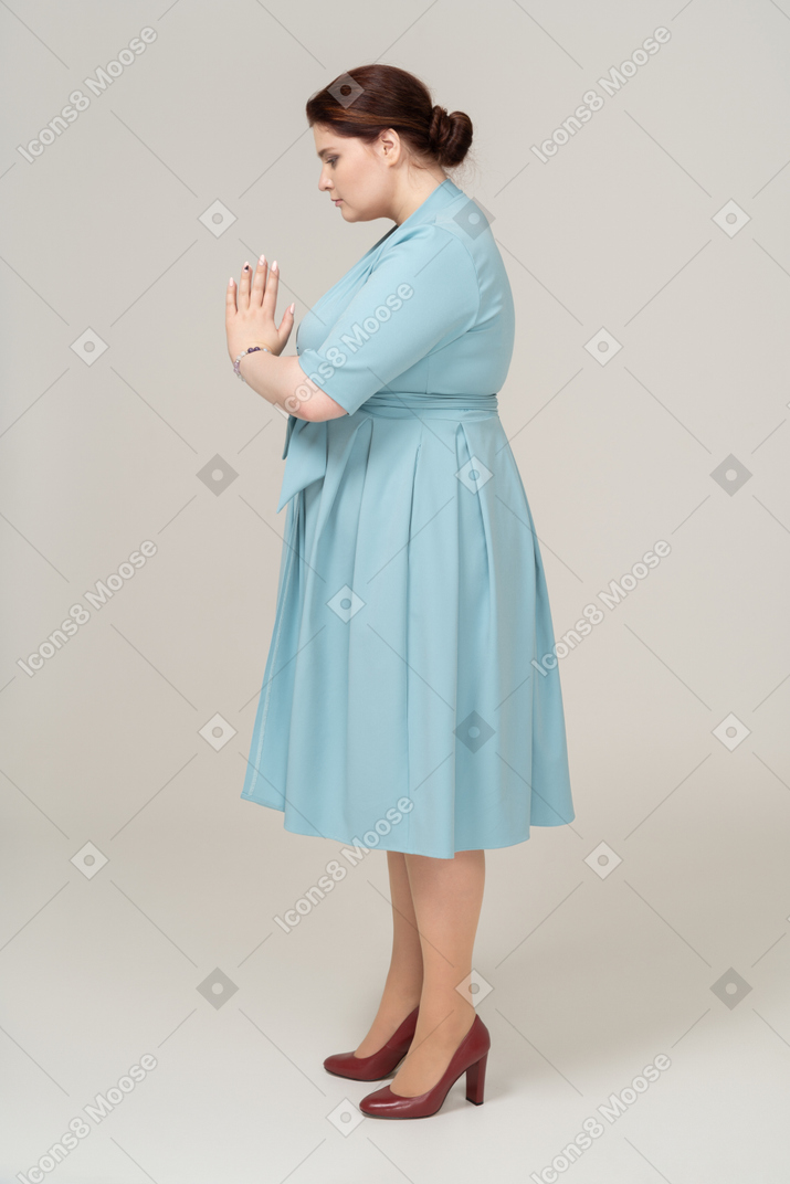プロフィールでポーズをとって青いドレスの悲しい女性