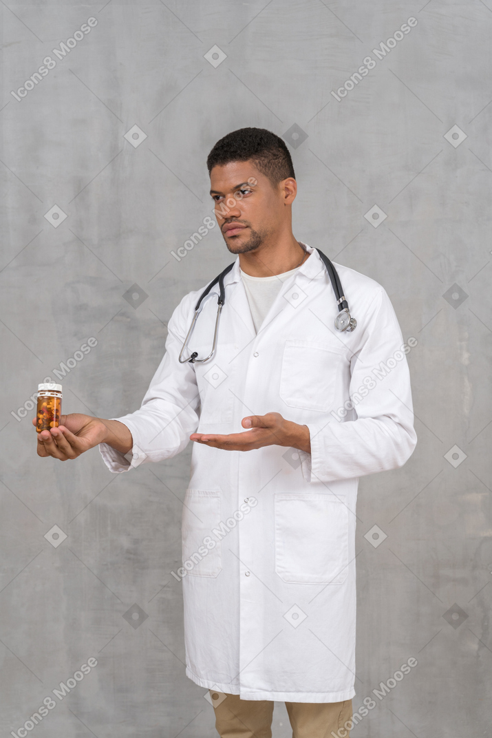 Jovem médico oferecendo um frasco de comprimidos