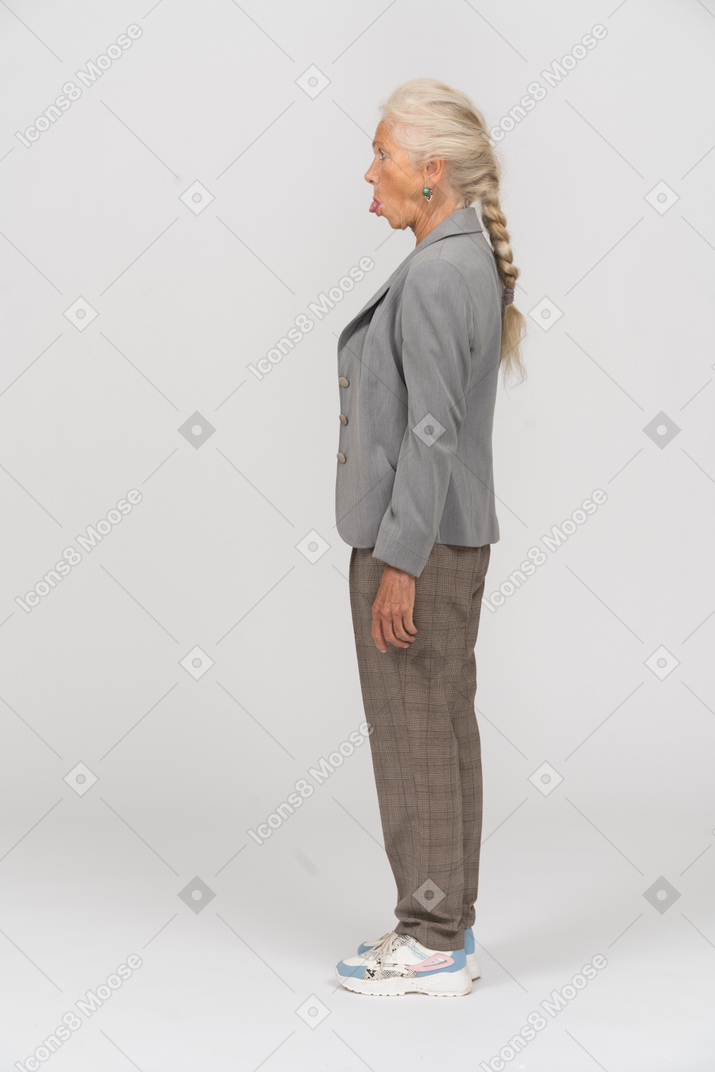 一位老妇人双臂交叉站立并露出舌头的侧视图
