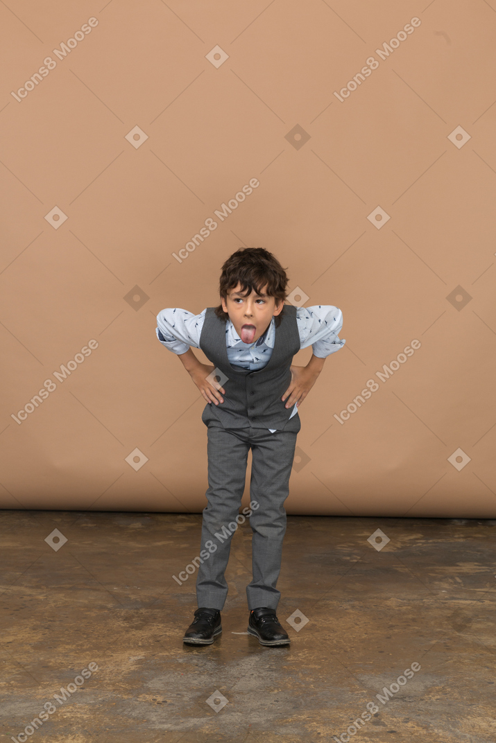 Vorderansicht eines jungen im anzug, der mit den händen auf den hüften steht und sich bückt