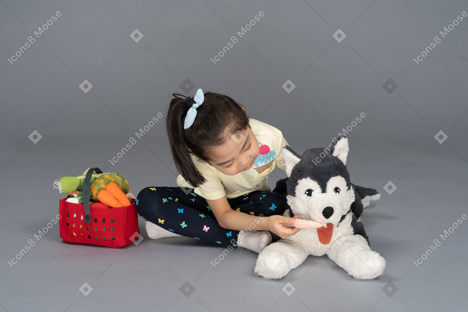 Portrait of a little girl feeding a dog plushie