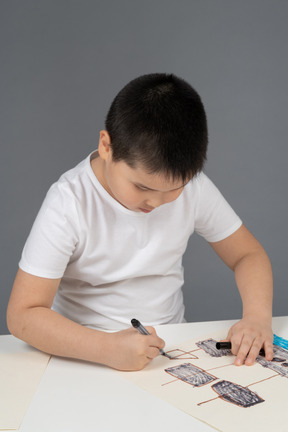 Smiling asian boy showing a drawing of a ship