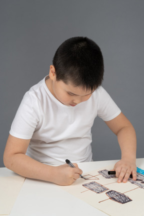 Ragazzo asiatico sorridente che mostra un disegno di una nave