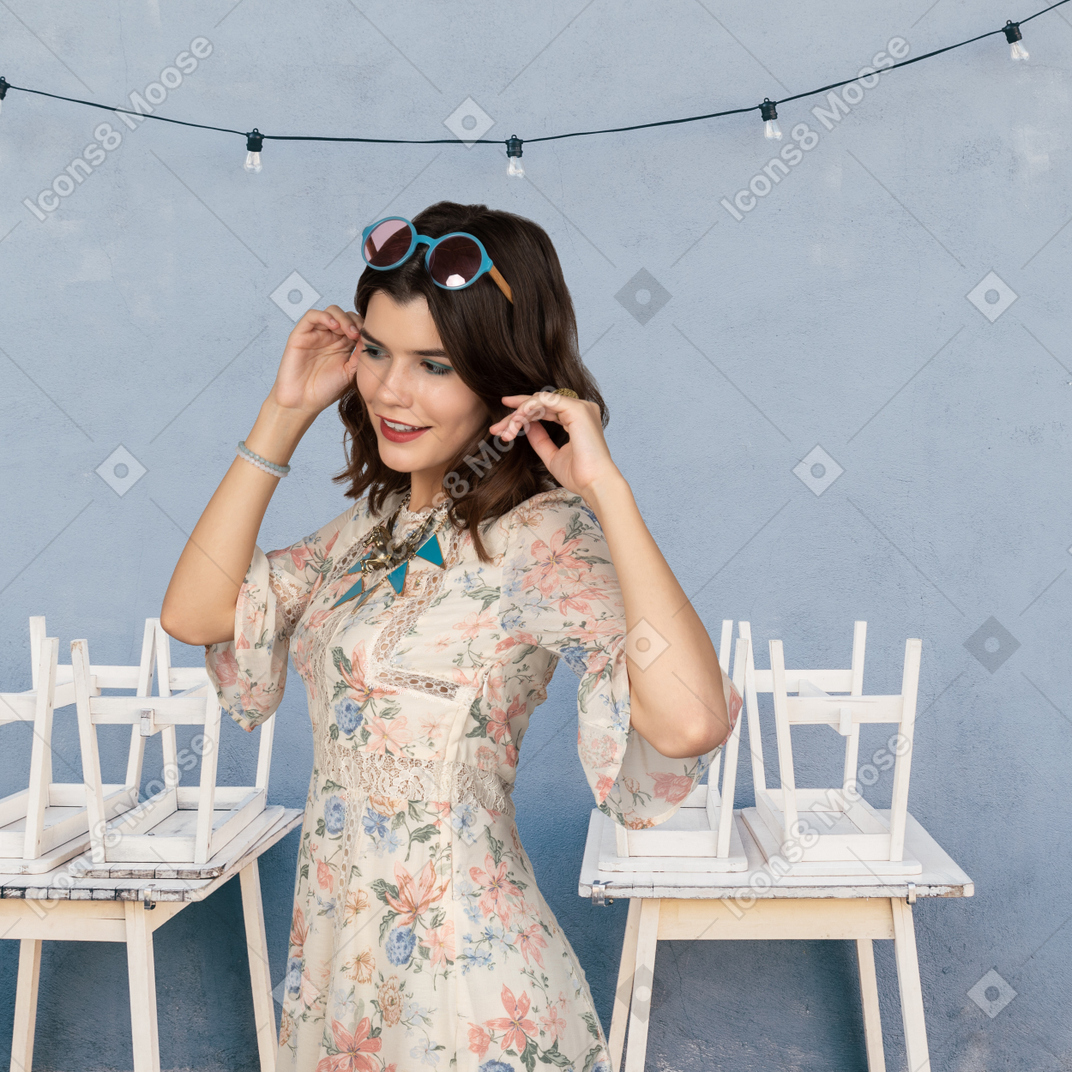 Woman in floral dress standing between two tables
