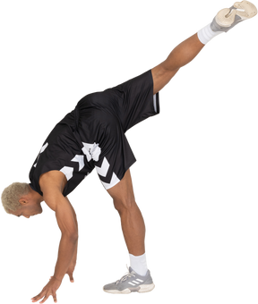 Vista lateral de un joven jugador de baloncesto masculino inclinado hacia adelante sobre sus brazos