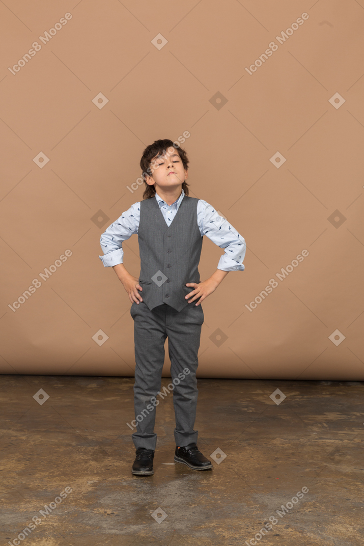 Front view of a boy in grey suit posing with hands on hips