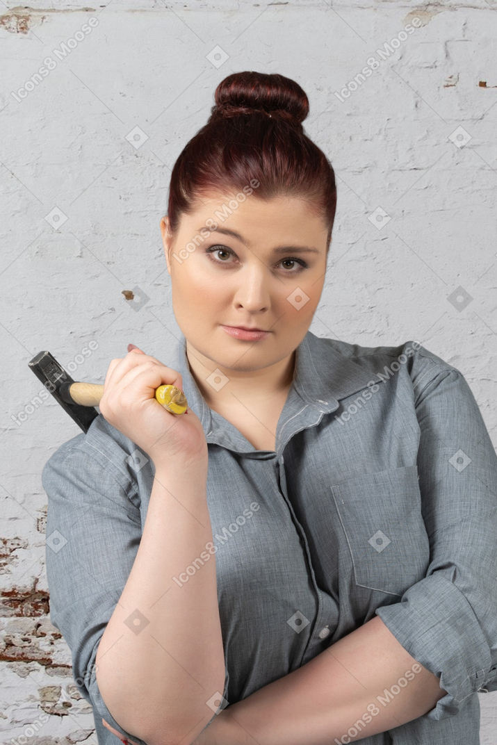 Woman holding a hammer and raising her brow