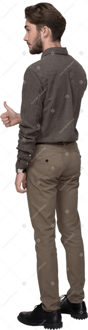 Vista posteriore di tre quarti di un giovane allegro in abiti da ufficio che mostra il pollice in su