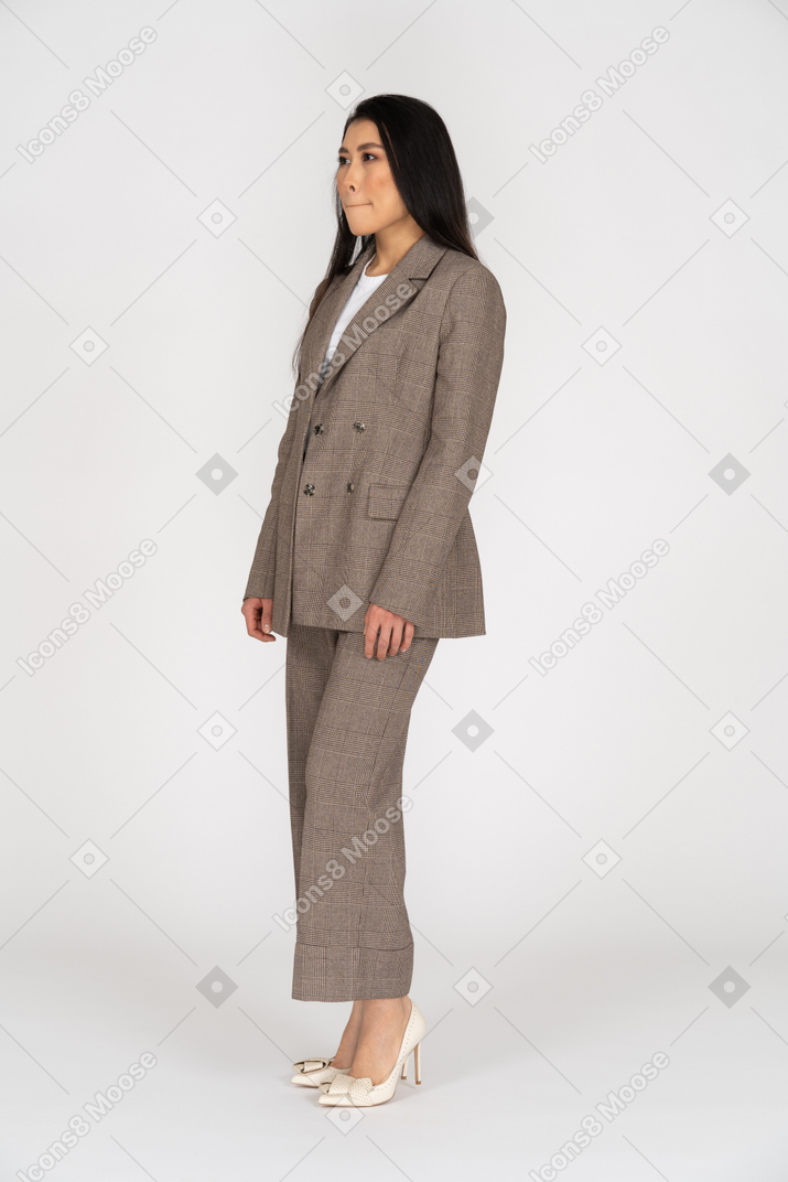 Three-quarter view of a young lady in brown business suit pressing lips