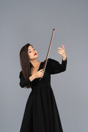 Vista frontale di una giovane donna in abito nero che fa l'impressione di suonare il violino