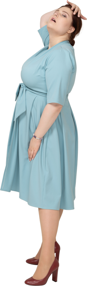 一个身着蓝色连衣裙、手放在头上摆姿势的女人的侧视图