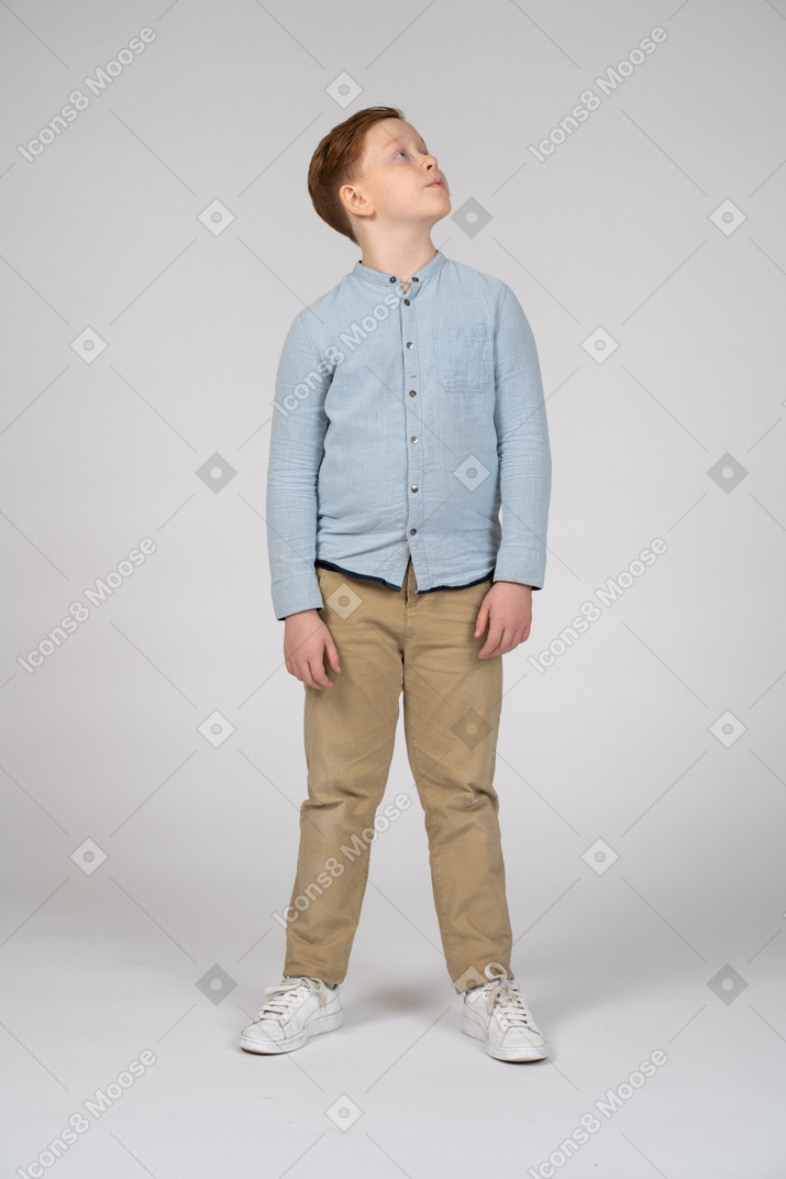 Vista frontal de un niño con ropa informal mirando hacia arriba