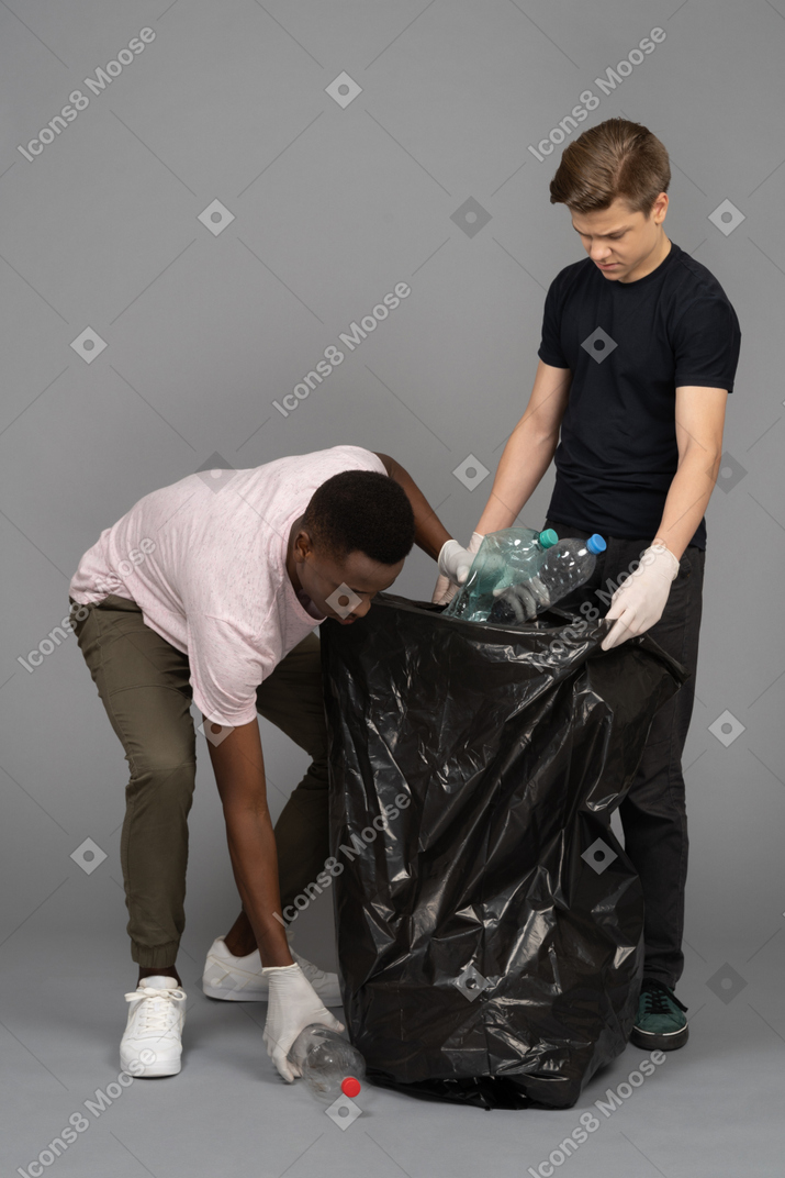 Young man collecting plastic bottles to put in a trash bag