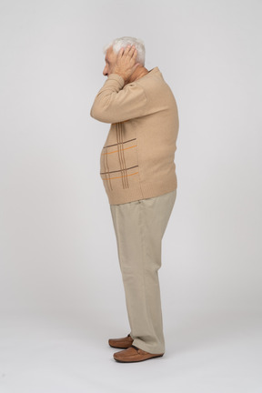 Vista laterale di un vecchio in abiti casual che coprono le orecchie con le mani