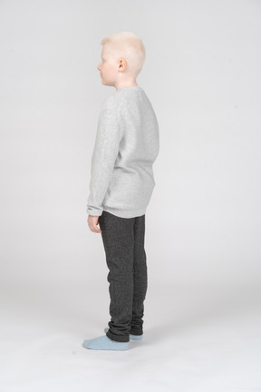 Side view of a blonde little boy in casual clothes standing  still