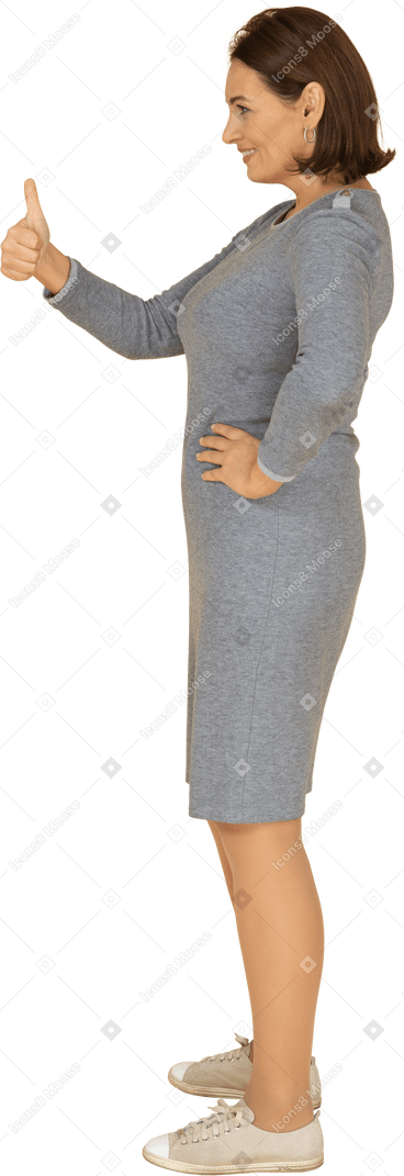 Side view of a woman in grey dress showing thumb up