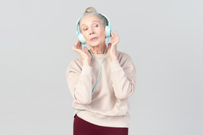 Old lady in listening music in headphones