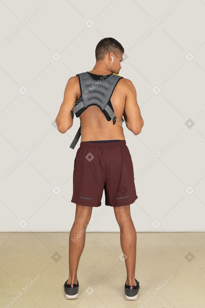 A back side view of the athletic guy wearing a life vest